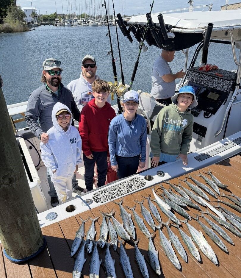 Fishing charter boat displaying large catch of Spanish mackerel laid out on deck at marina
