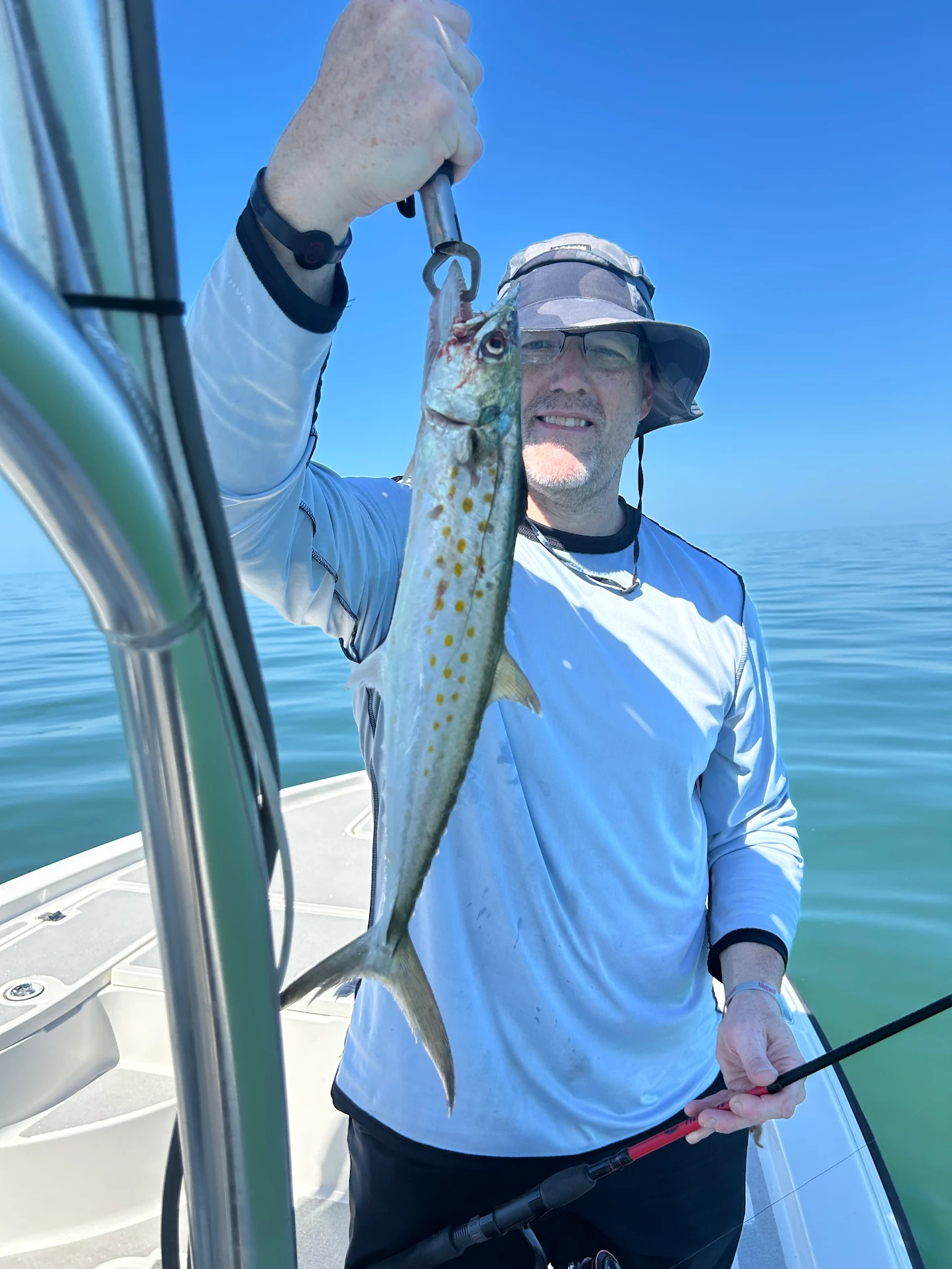 Angler holding freshly caught Spanish mackerel on fishing boat