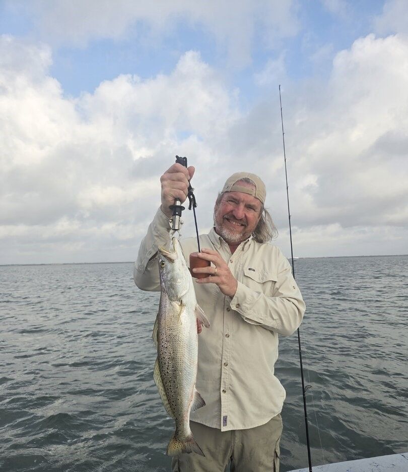 Angler holding freshly caught speckled trout while fishing on open water