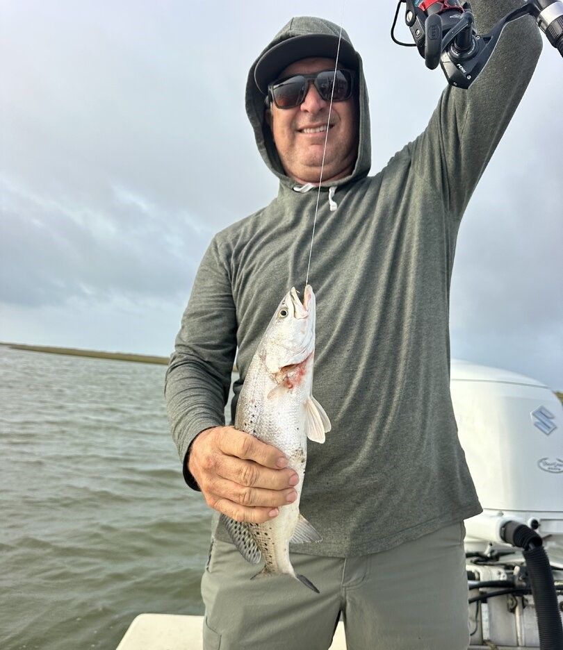 Freshly caught speckled trout held up on fishing boat