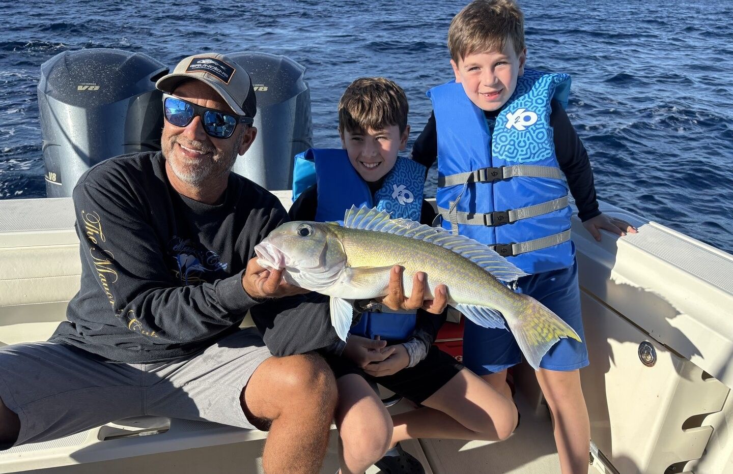 Fishing boat with caught fish being displayed on deck over ocean water