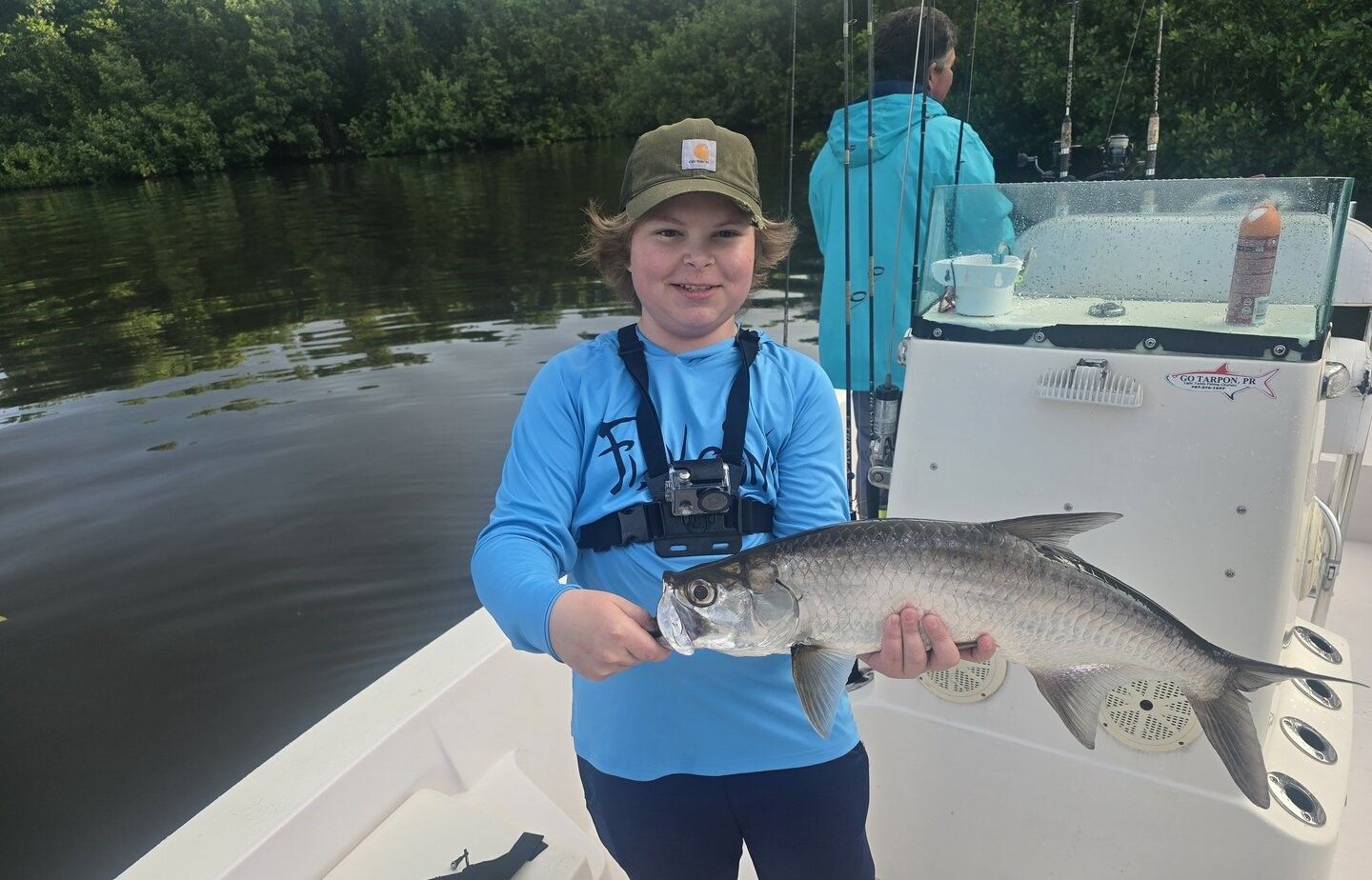 Angler holding caught tarpon fish on fishing boat