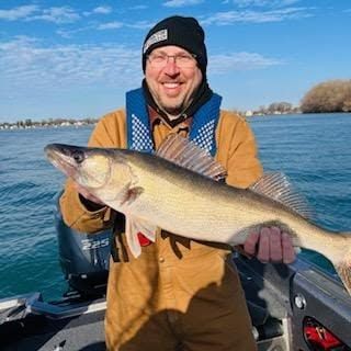 Freshly caught walleye held up on fishing boat with water in background