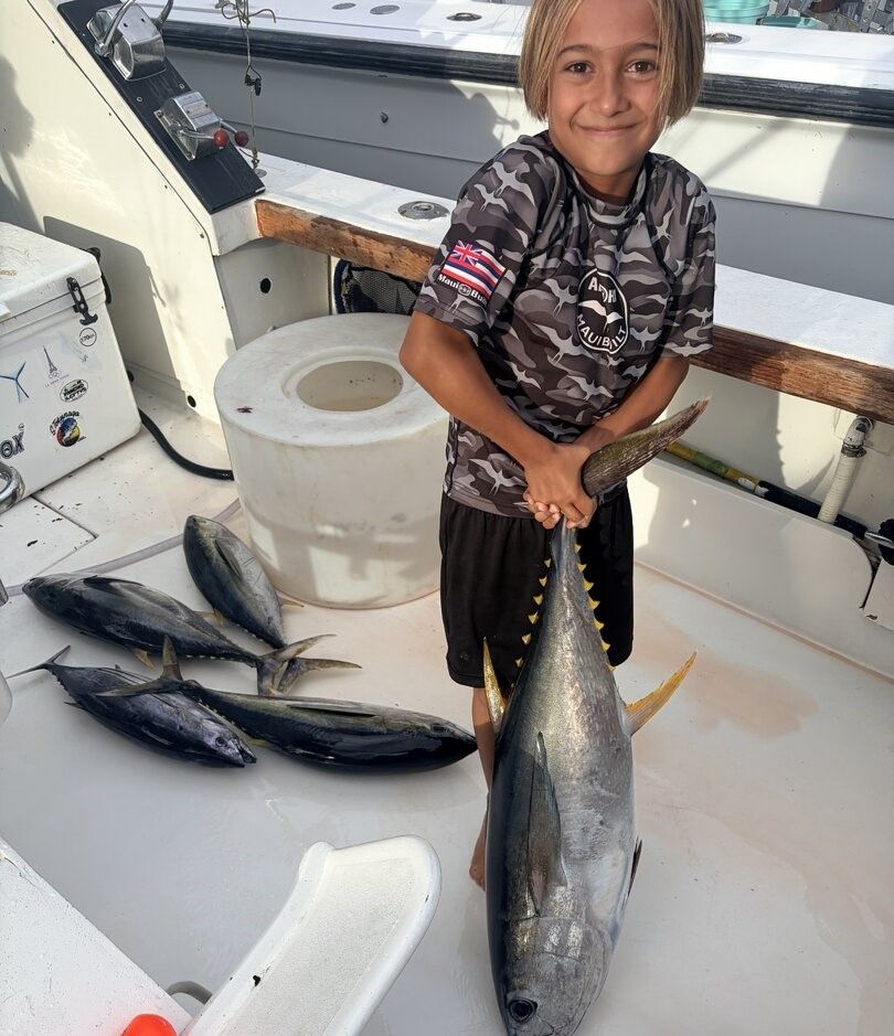 Yellowfin tuna catch displayed on boat deck with fishing rods