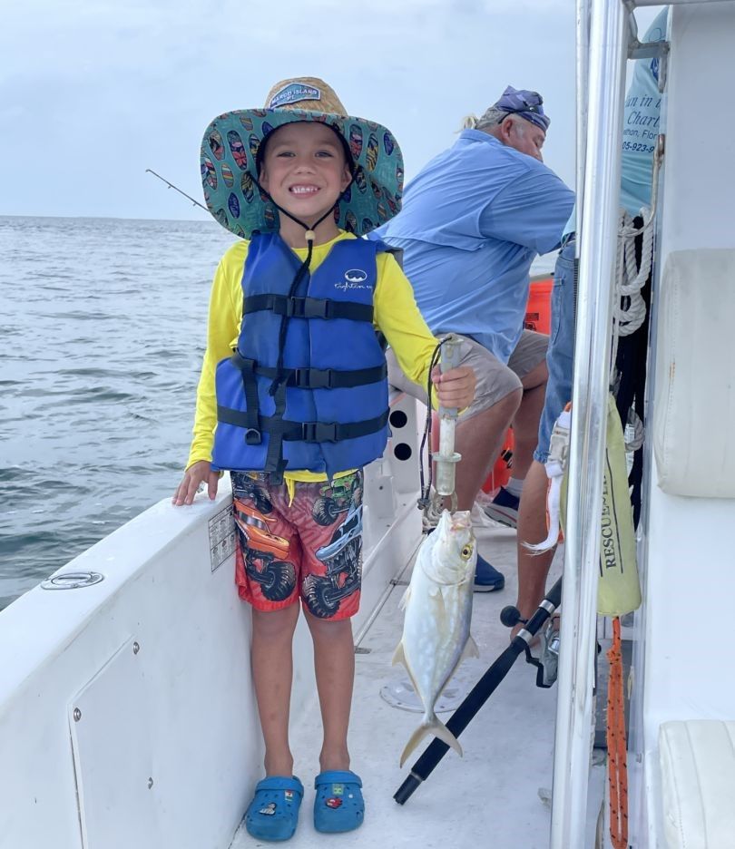 Young angler on fishing boat deck with catch displayed
