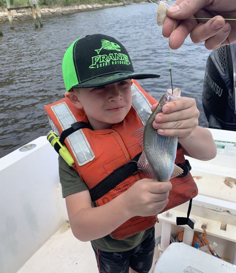 Young angler holding freshly caught fish on fishing boat