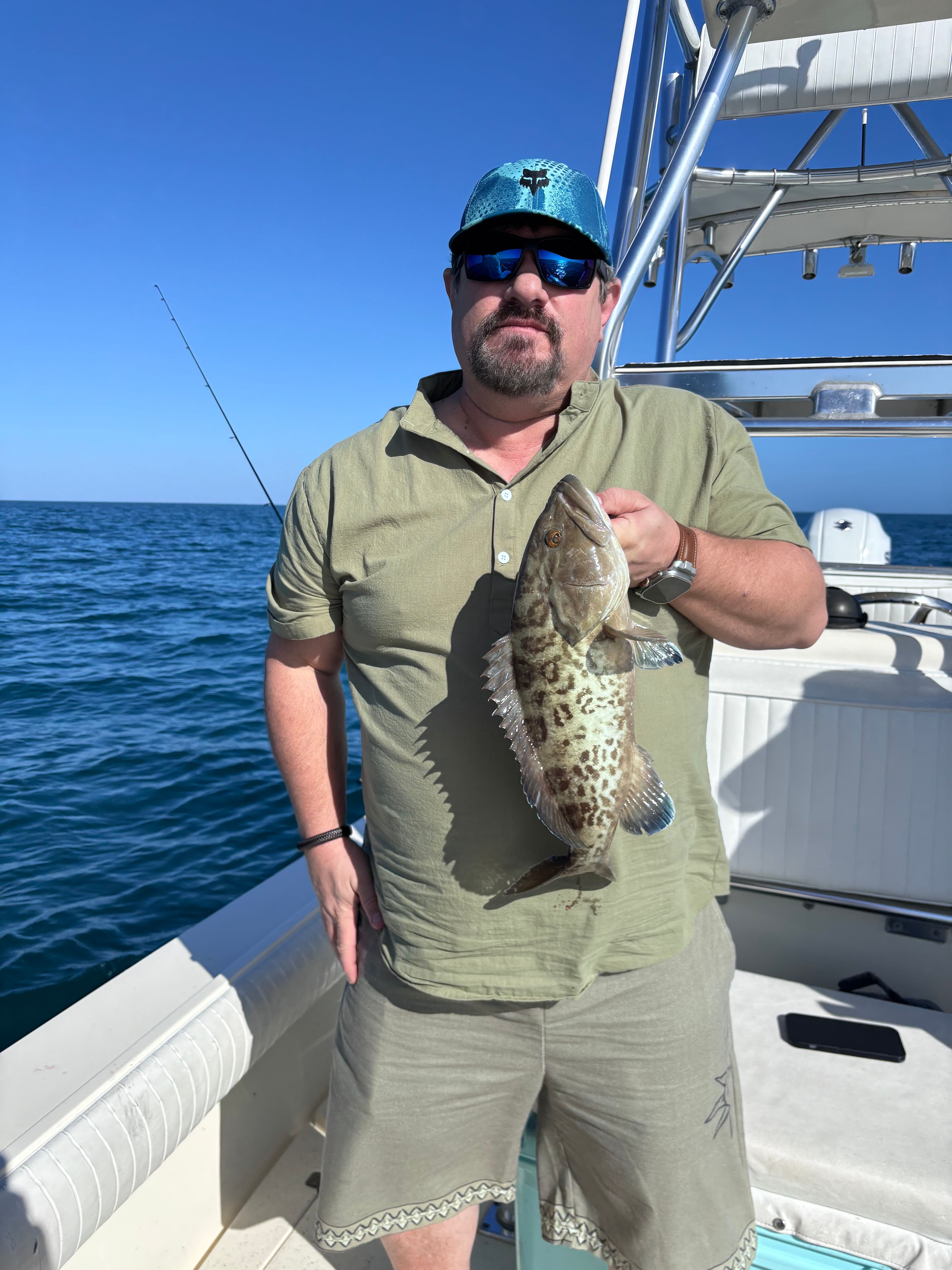 Freshly caught gag grouper being displayed on fishing boat deck over blue ocean water