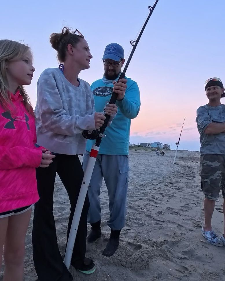 Group of people fishing on sandy beach at sunset with fishing rods