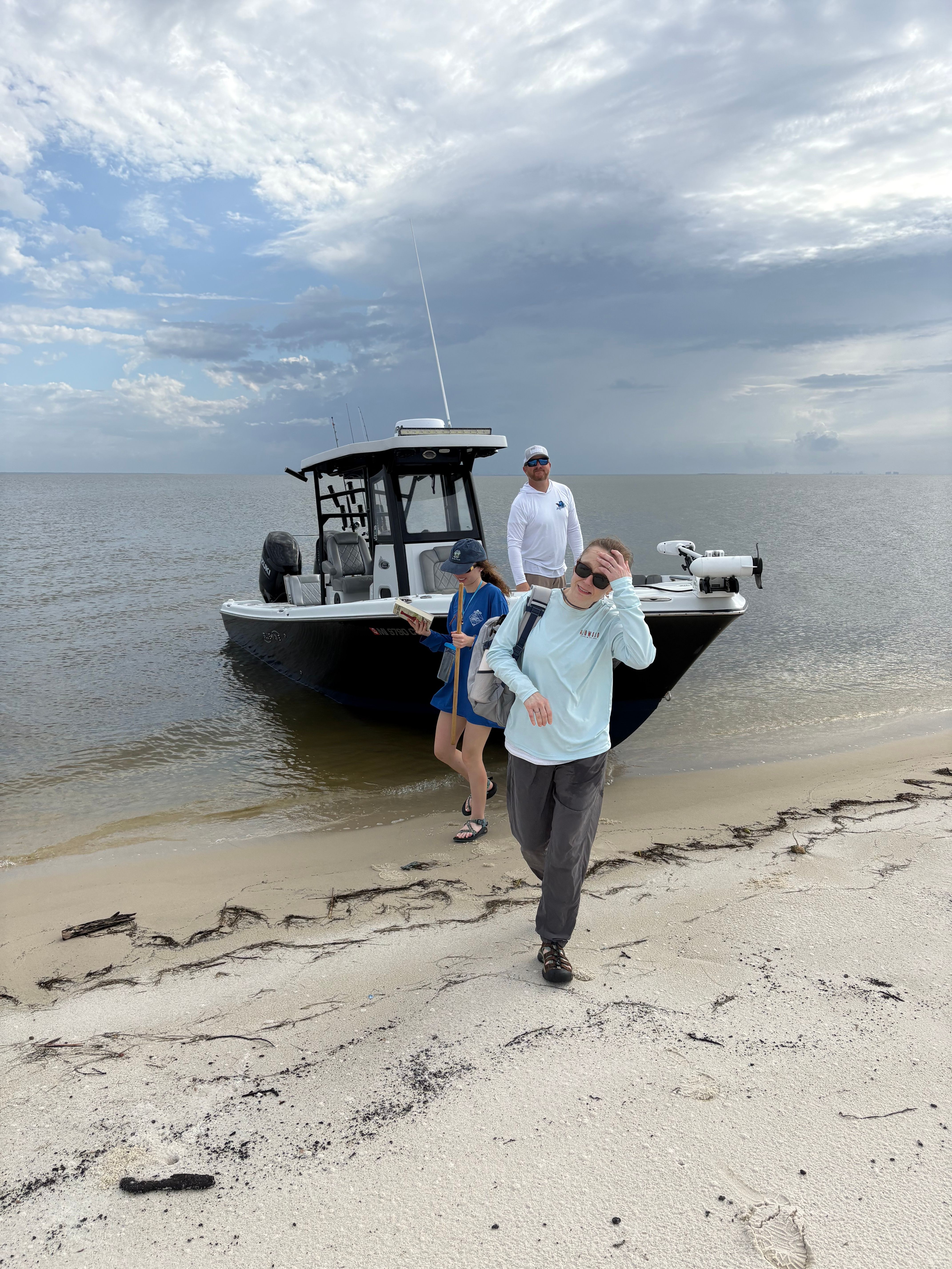 Beach scene with boat on sandy shore under cloudy sky