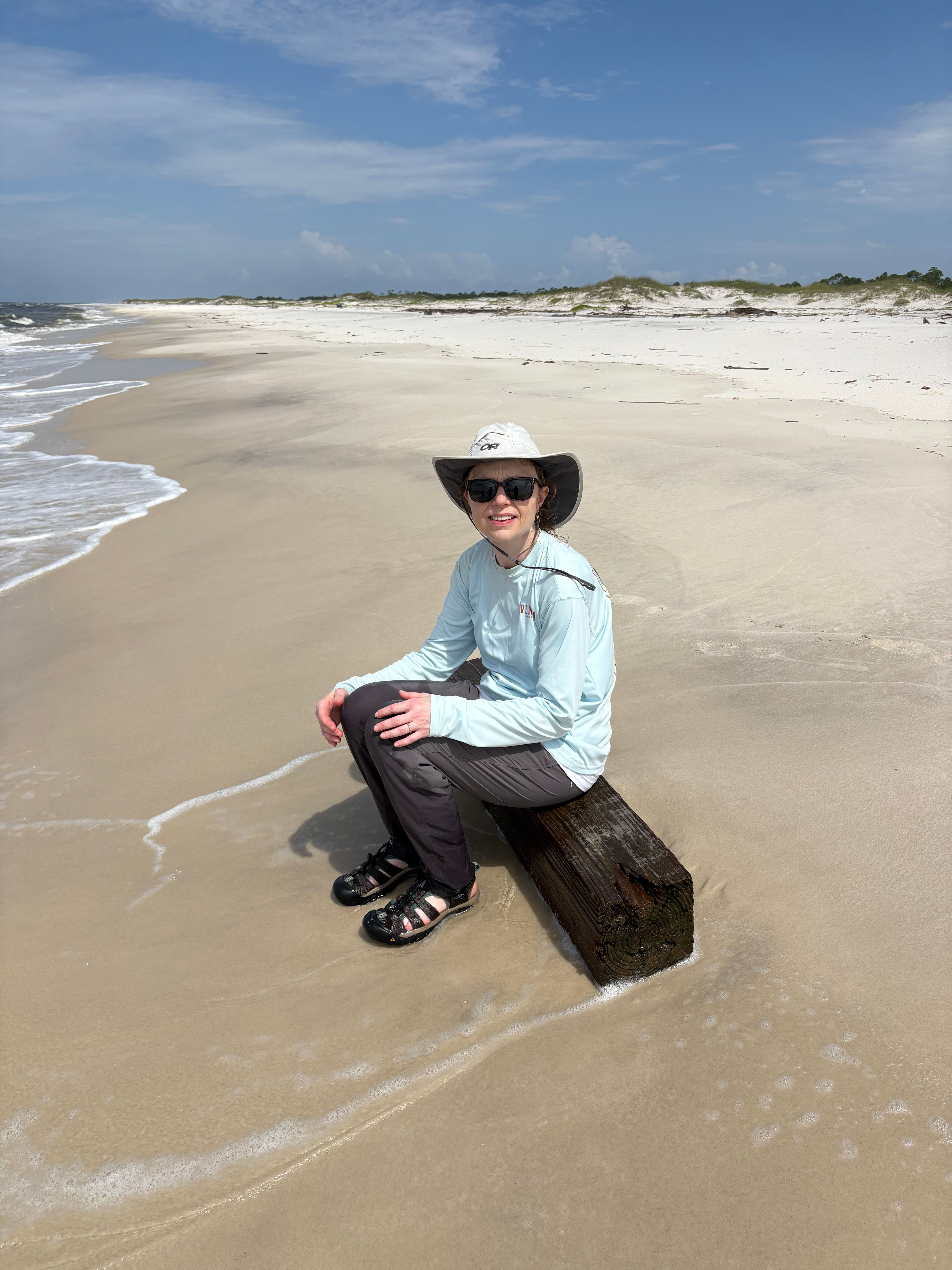 Beach scene with wooden post on sandy shore and ocean waves