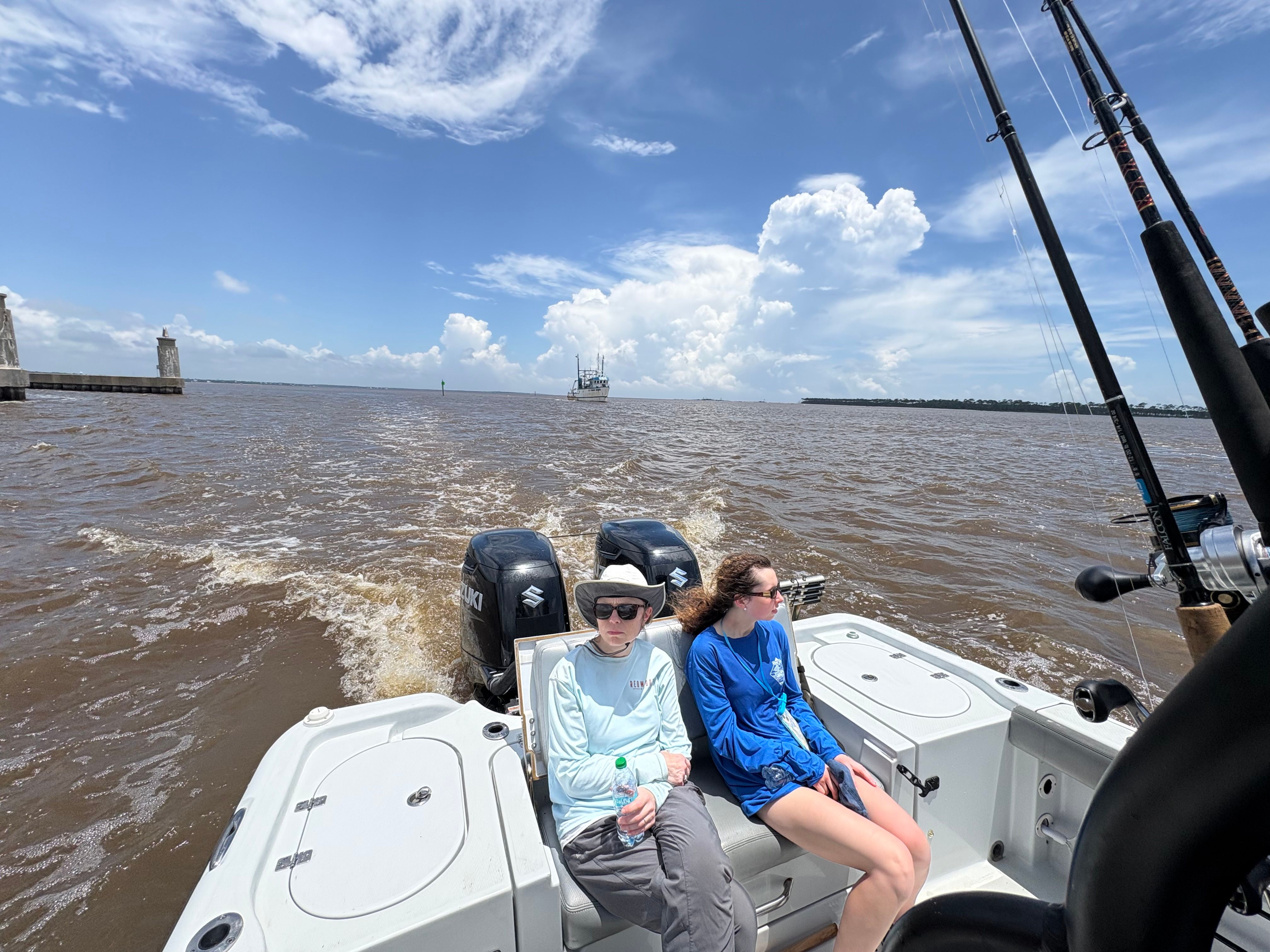 Fishing boat with twin outboard motors on open water with fishing rods visible