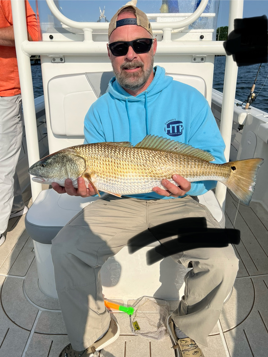 A mighty Redfish reeled in by a skilled angler on a partly cloudy day.