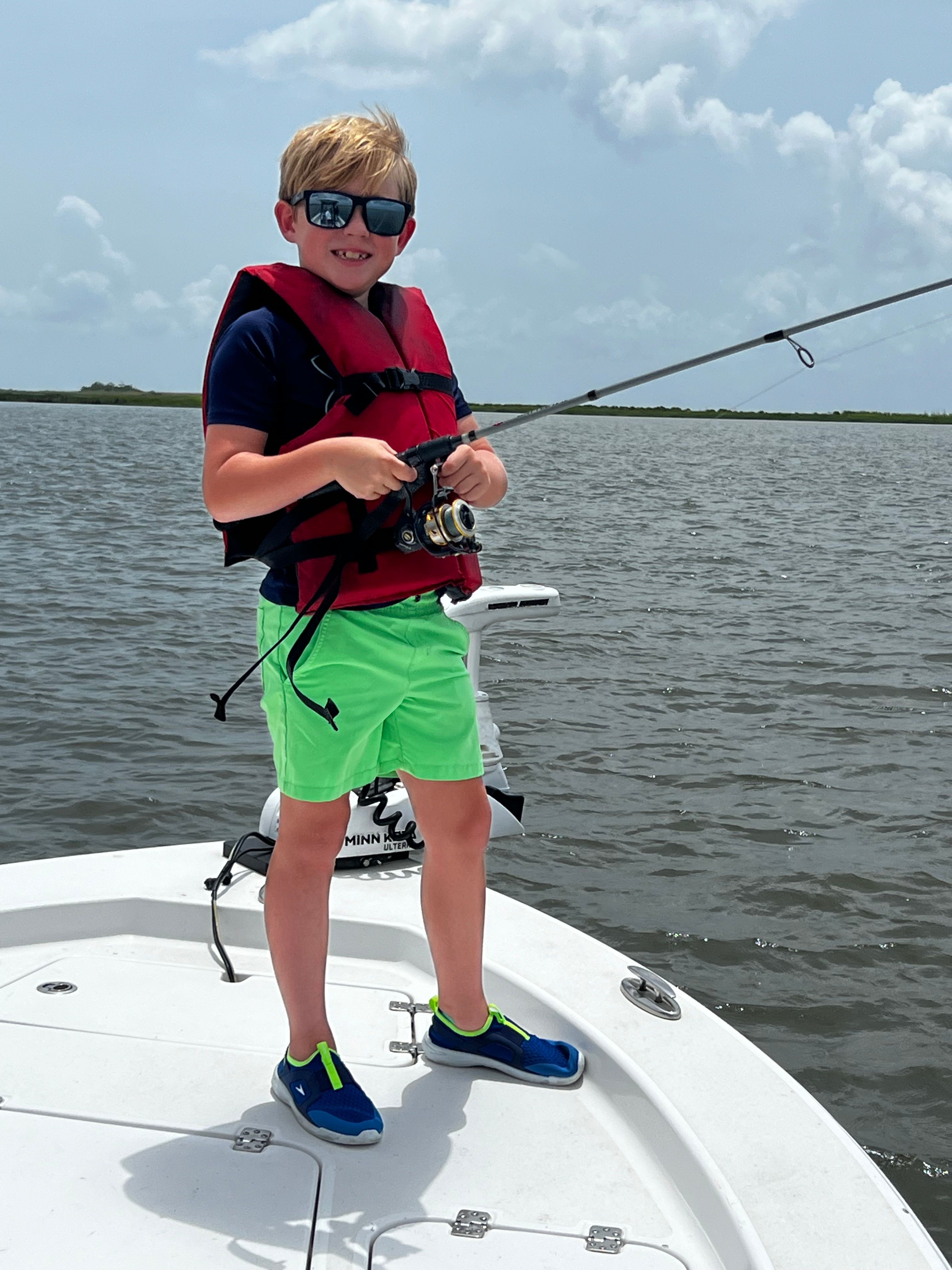 Angler holding fishing rod on white boat deck with ocean water in background