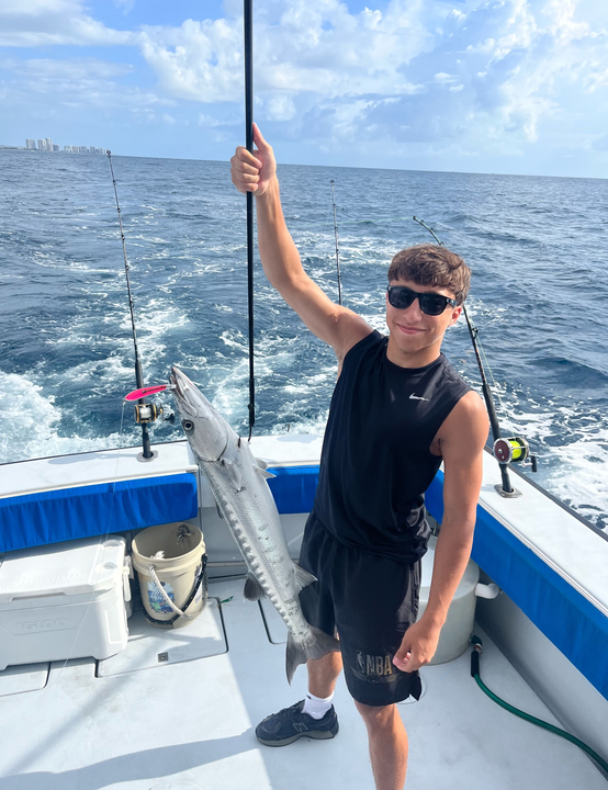 Reeling in a big Great Barracuda under partly cloudy skies!