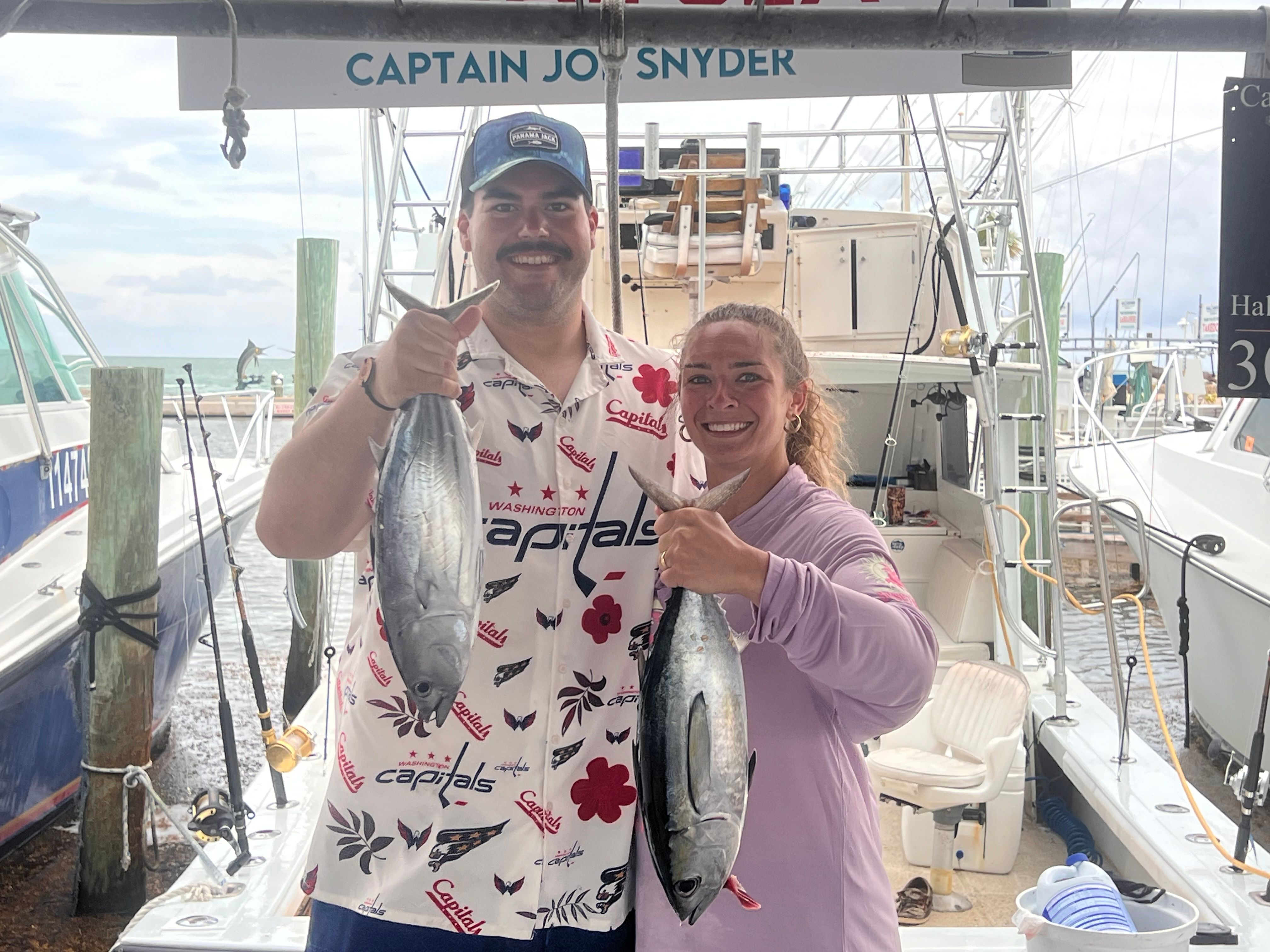 Two anglers displaying their catch of blackfin tuna and skipjack tuna on a fishing charter boat