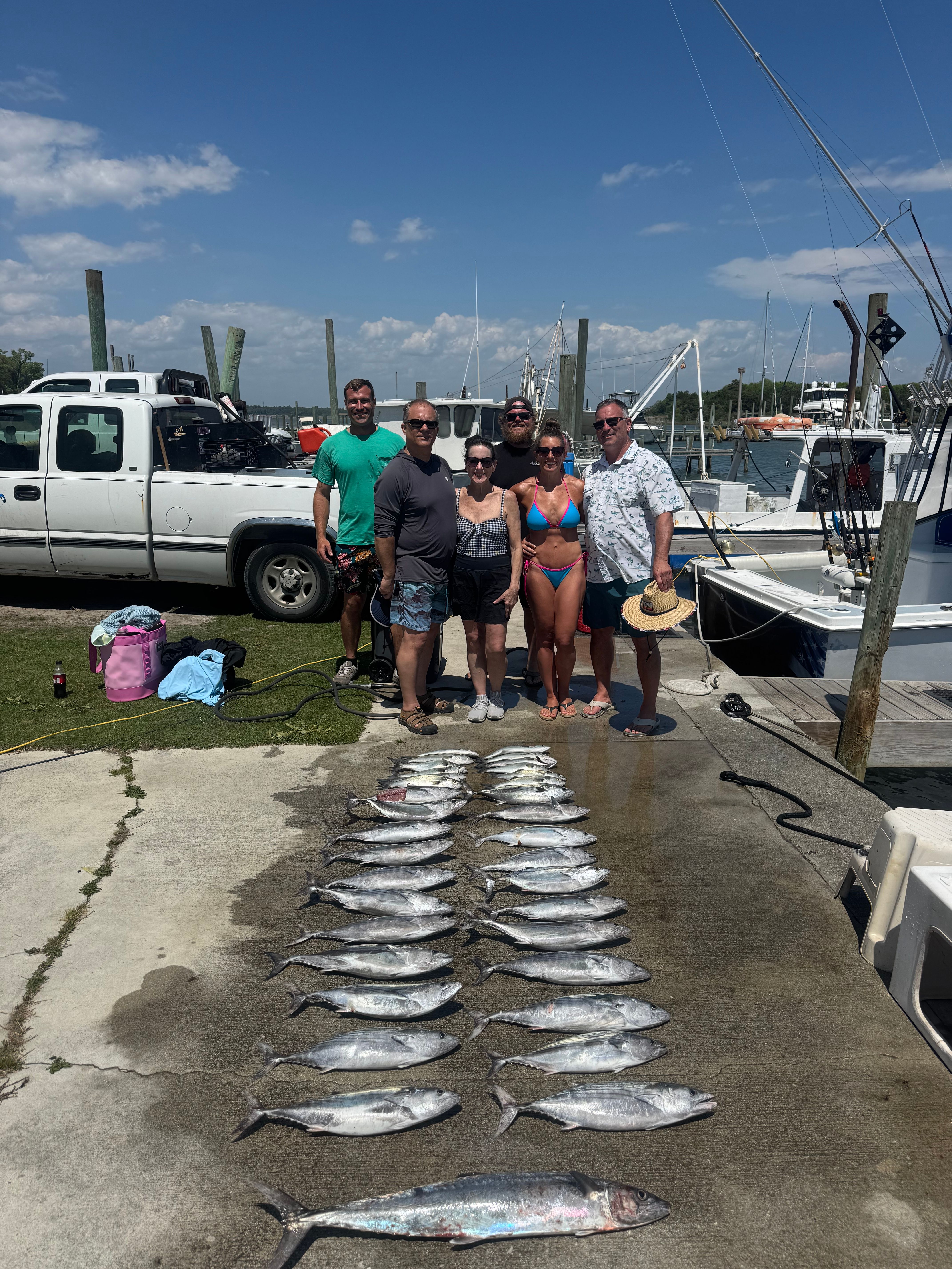 Fishing charter displaying catch of King Mackerel and Atlantic Bonito laid out on dock
