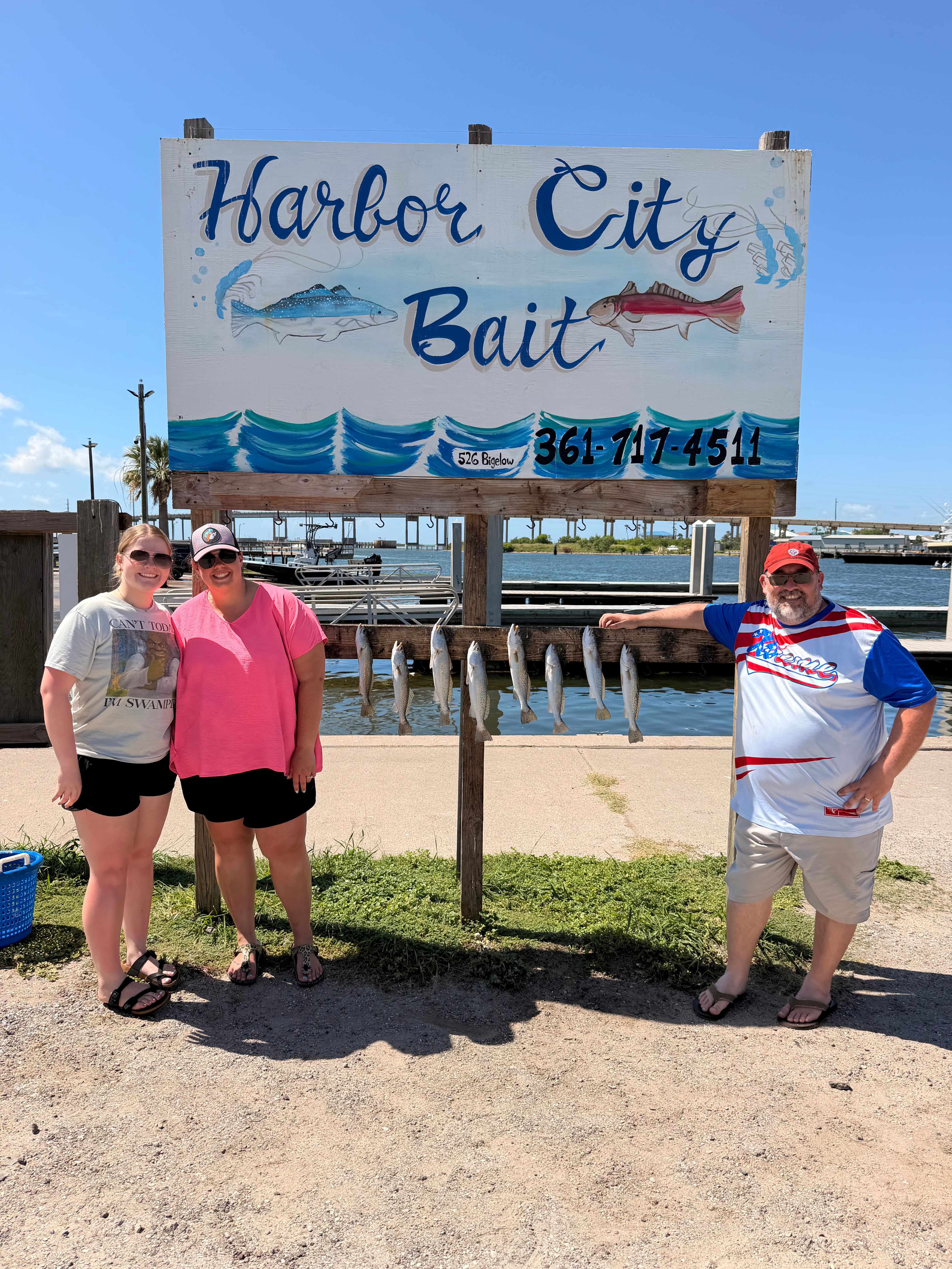 Fishing charter boat with Harbor City Bait sign and cleaning station at marina dock