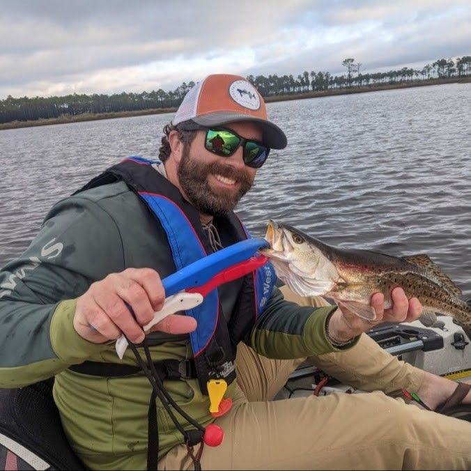 A lone fisherman casting a line in an unknown location