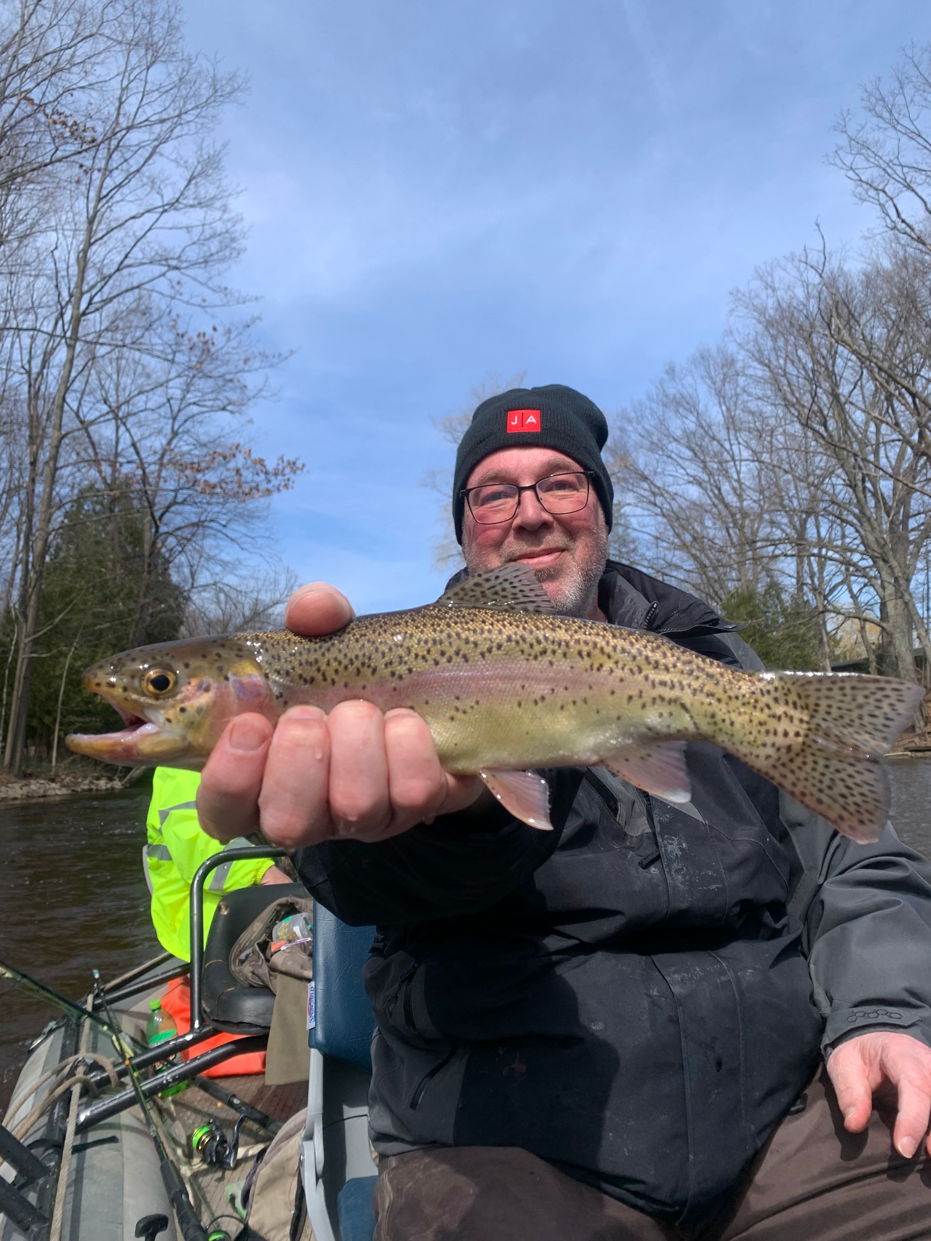 Angler holding freshly caught rainbow trout during outdoor fishing trip