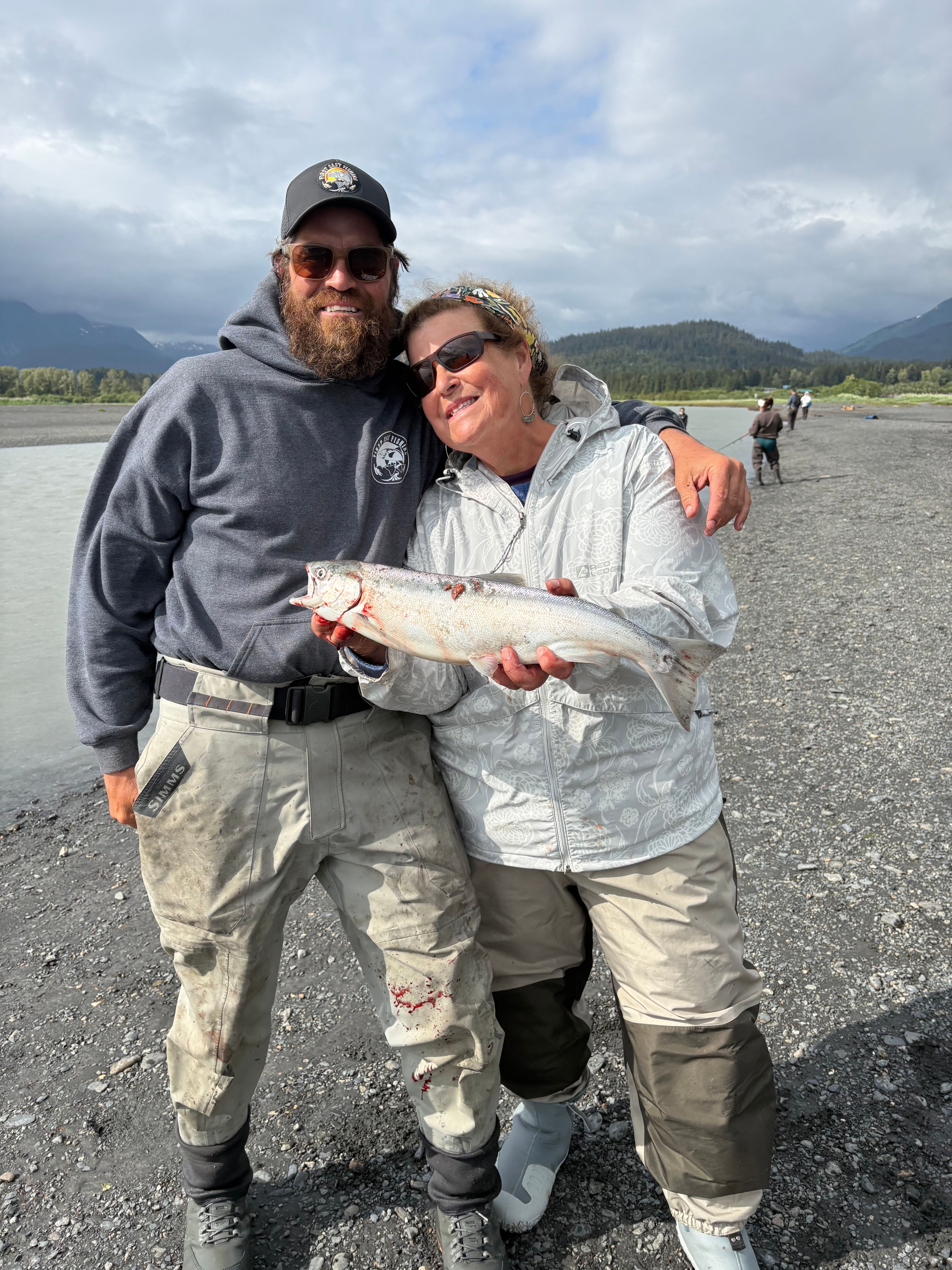 Two anglers displaying a freshly caught Coho Salmon during an outdoor fishing trip