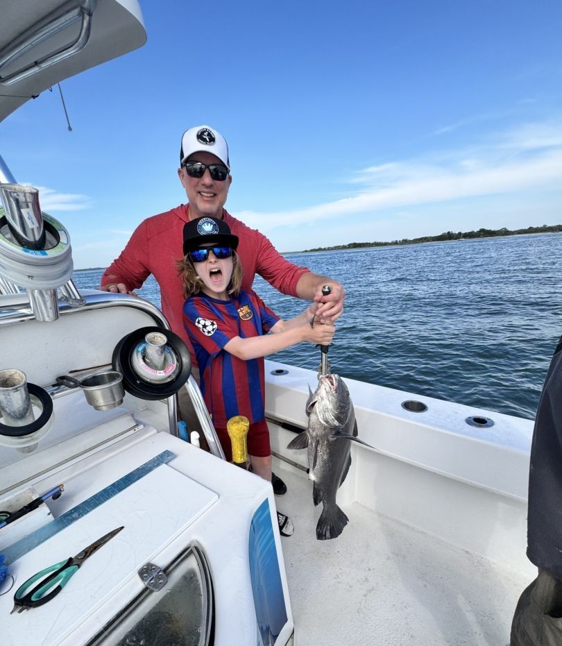 Anglers catching a black drum fish while fishing