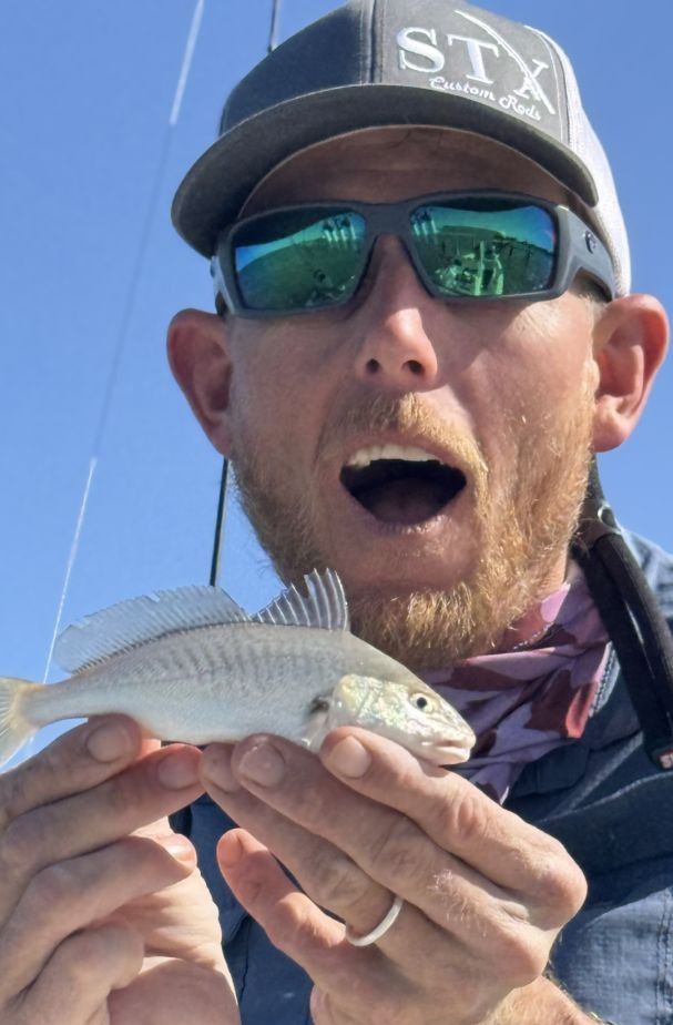 Atlantic croaker fish being held up after successful catch on fishing trip