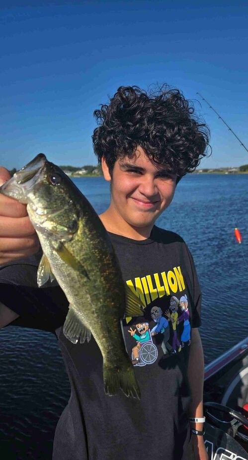 Freshly caught bass being held up during fishing trip on lake