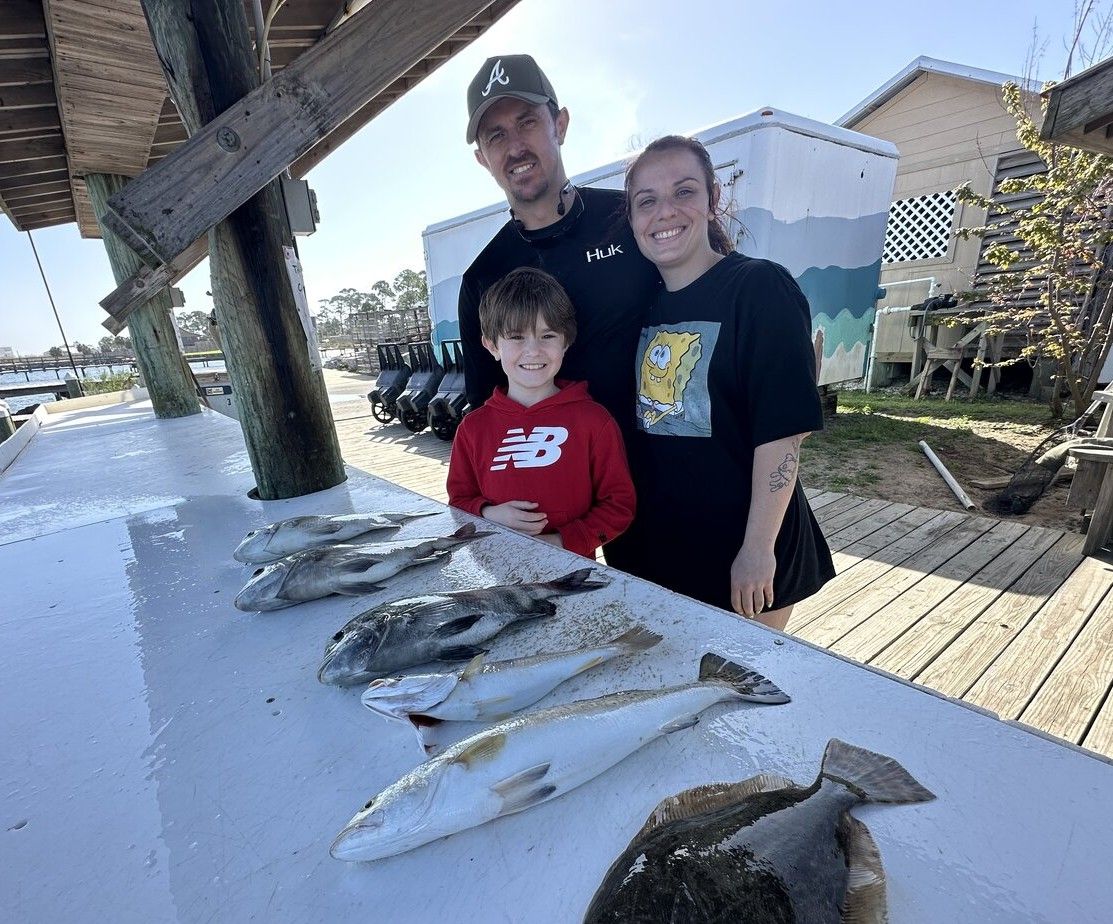 Family fishing trip with catch of black drum and other fish displayed on cleaning table at marina