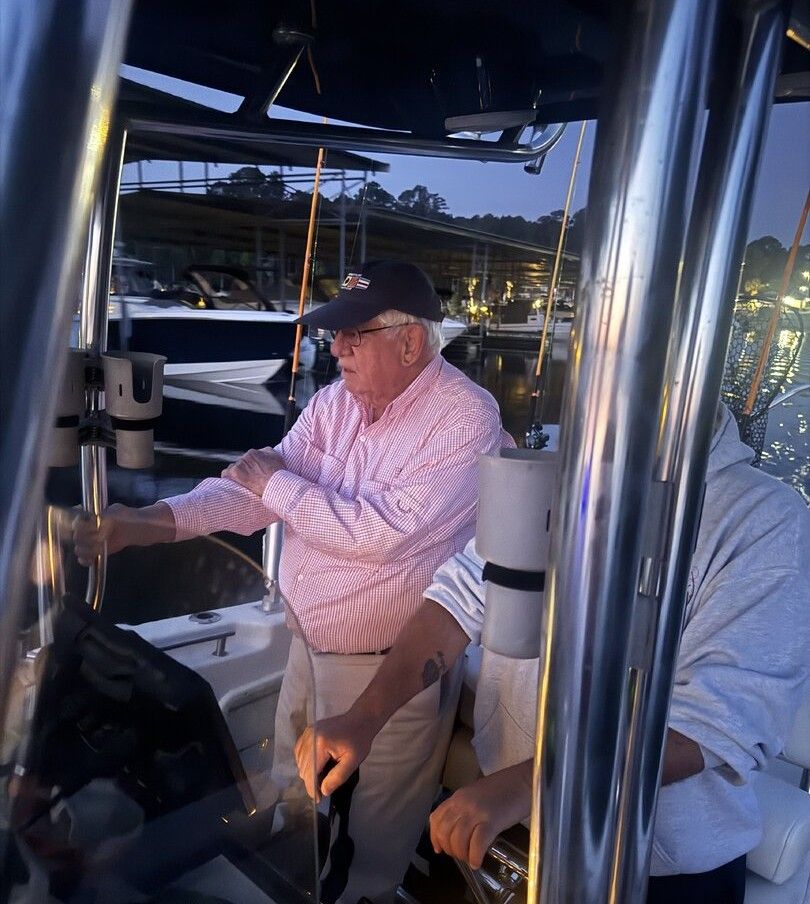 Boat captain at helm steering vessel in marina with other boats visible in background