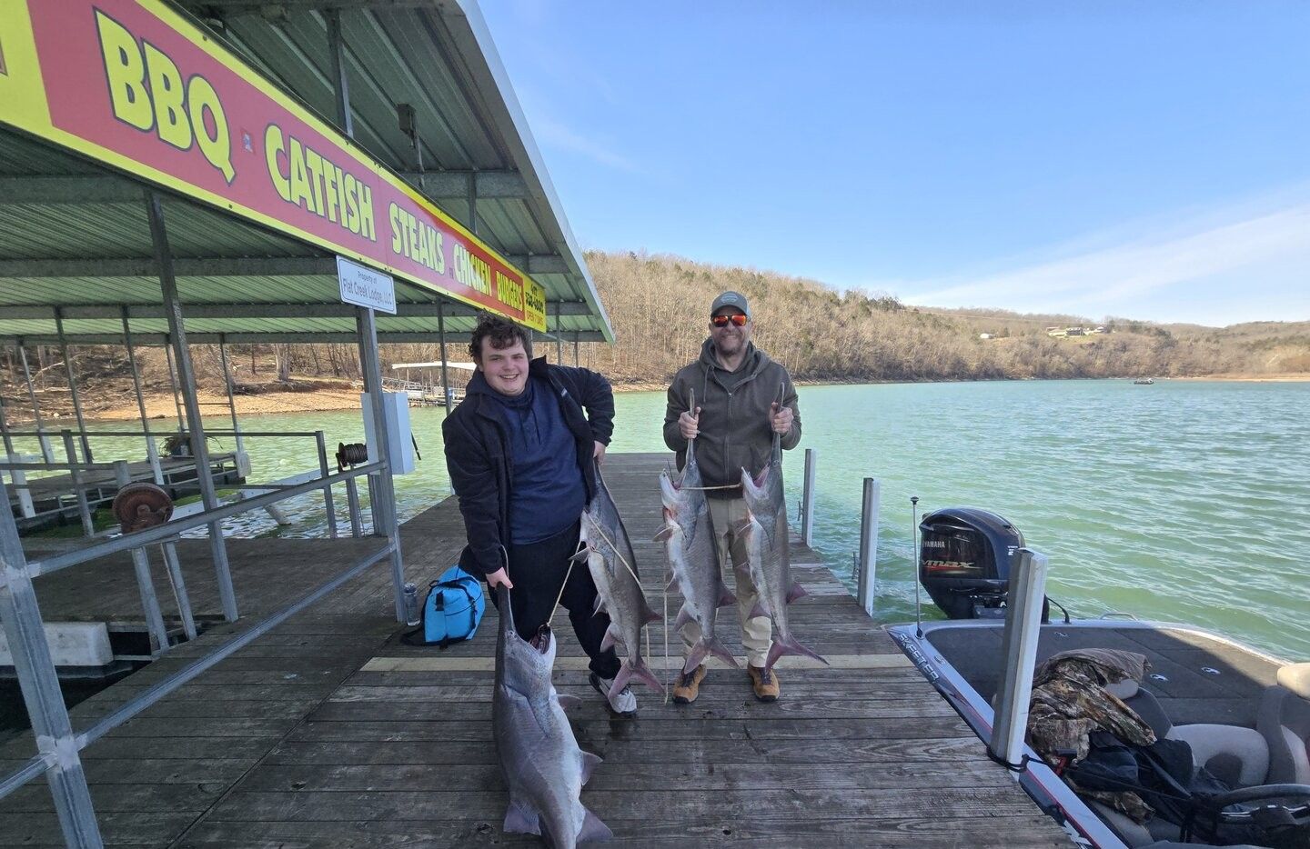 Successful fishing trip showing multiple large catfish displayed on wooden dock at lake marina