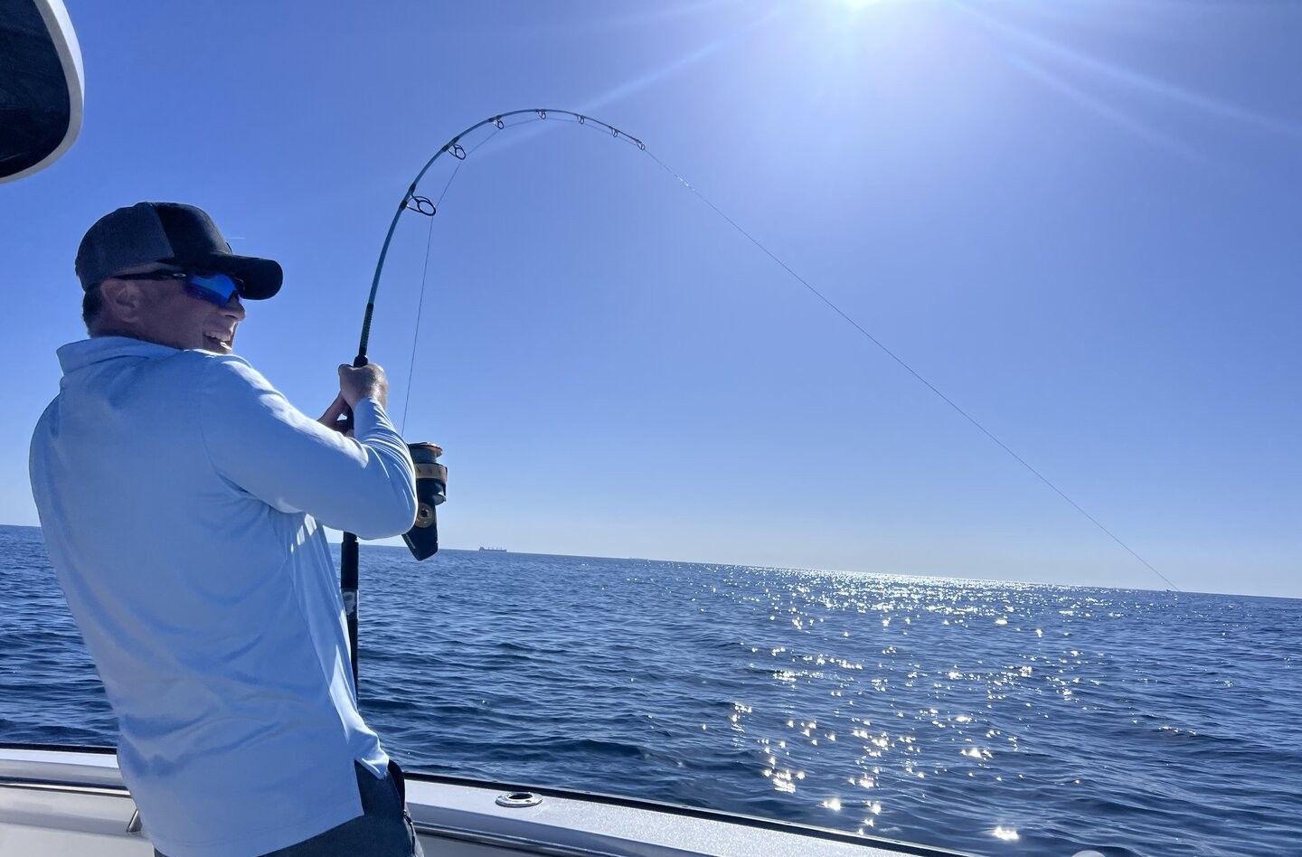 Deep sea fishing with bent rod showing fish on the line over ocean waters