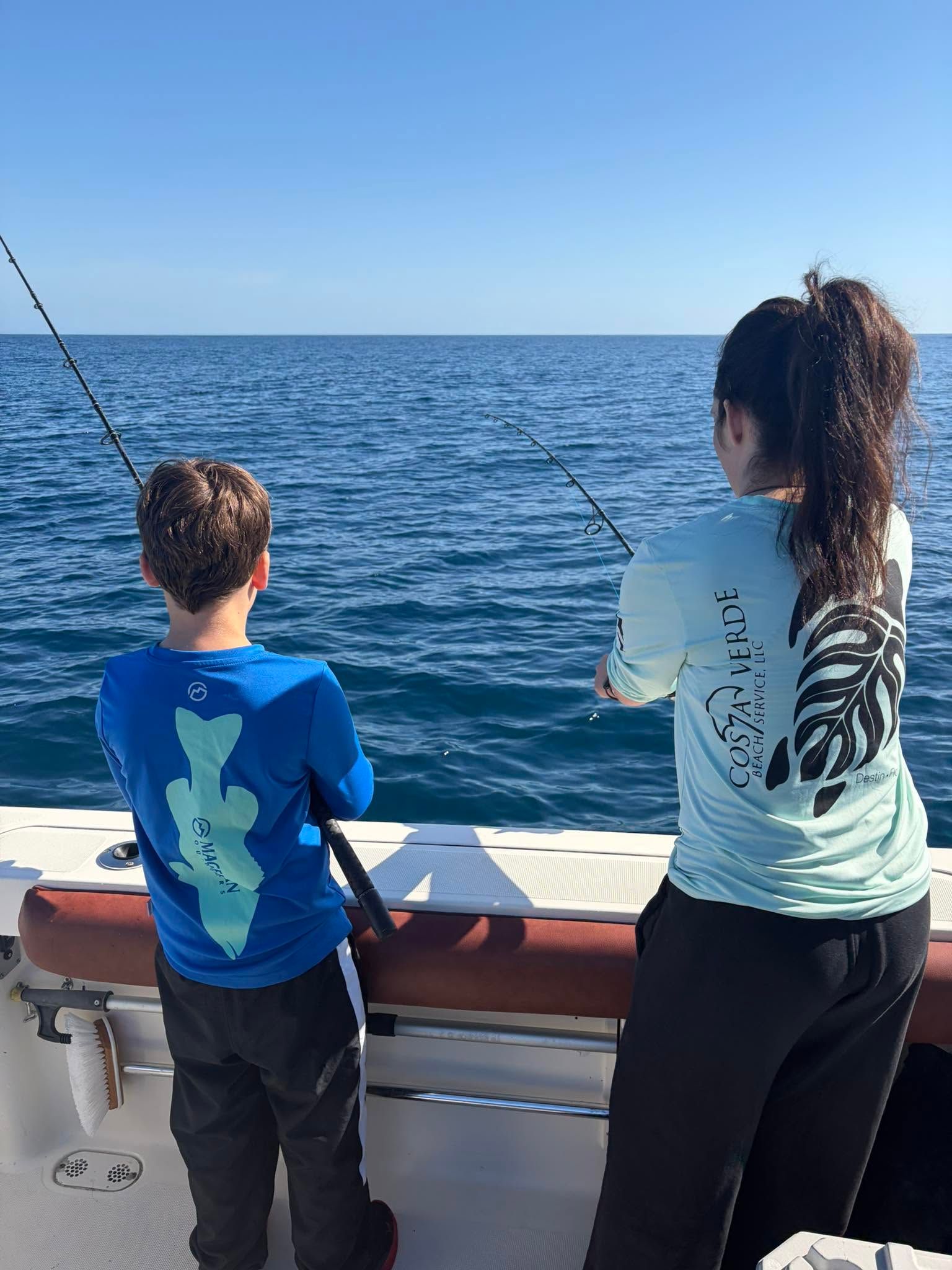 Deep sea fishing from boat deck with fishing rods cast into blue ocean water