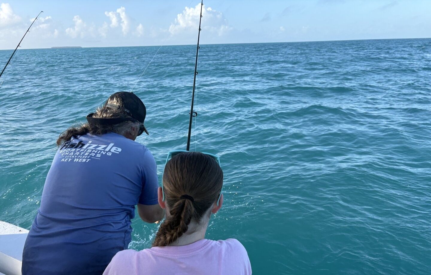 Deep sea fishing from boat with fishing rods extended over blue ocean water