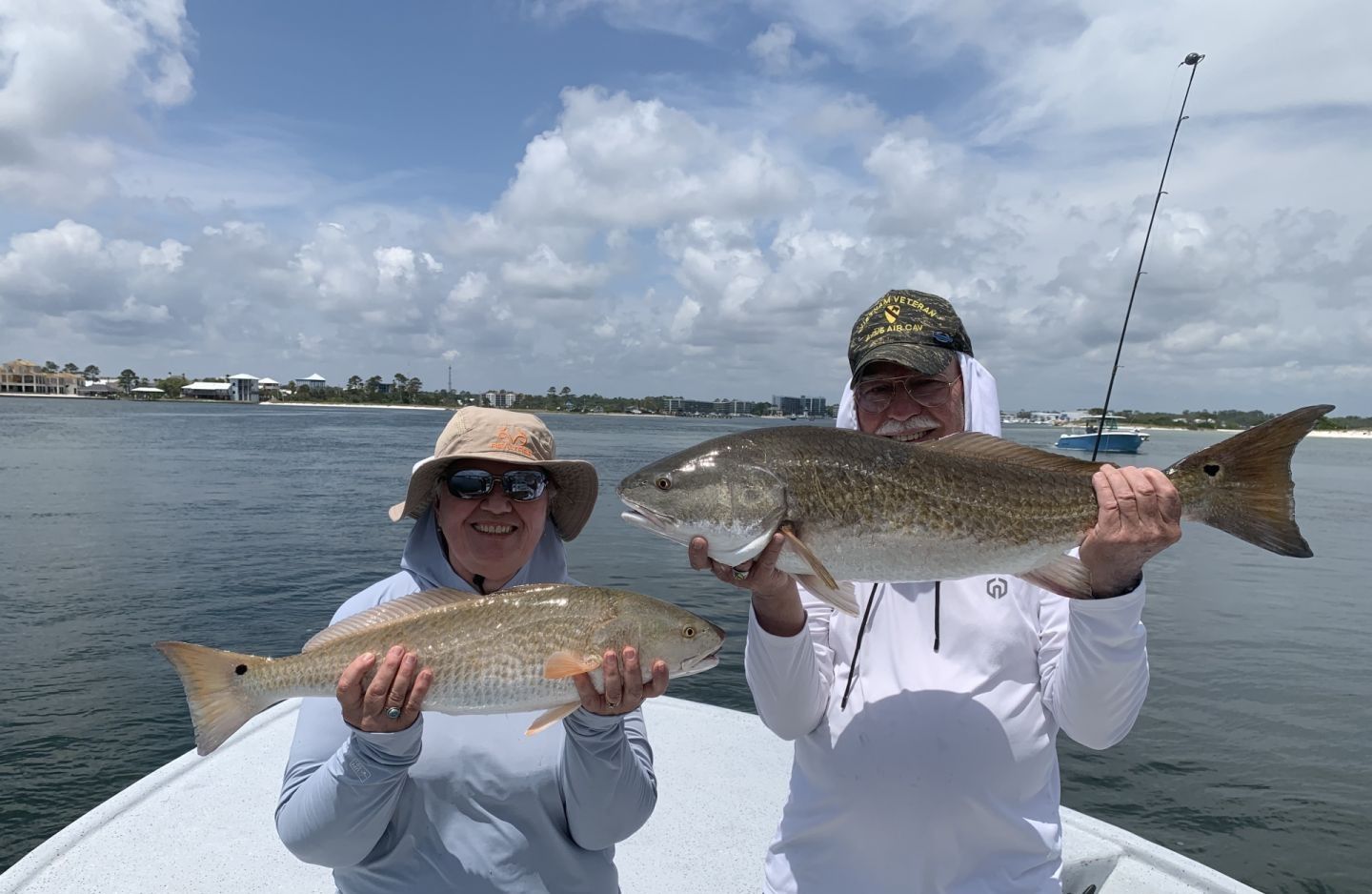 Two anglers displaying freshly caught redfish on fishing boat