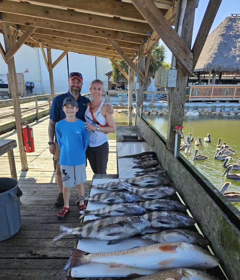 Family fishing trip with impressive catch of redfish and sheepshead displayed on wooden dock with pelicans nearby