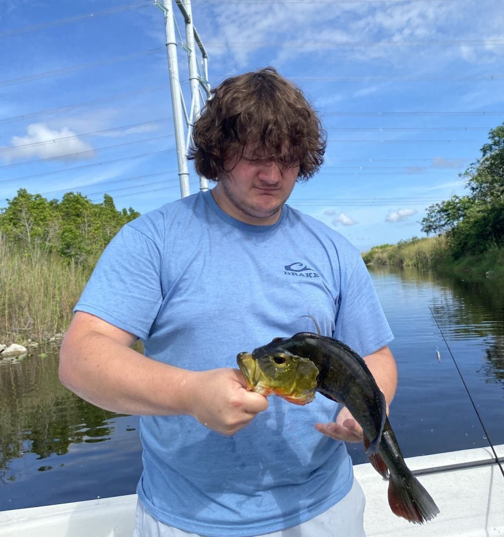 Angler holding freshly caught fish on boat in calm waterway