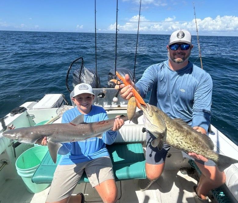 Two anglers displaying freshly caught gag grouper on fishing boat