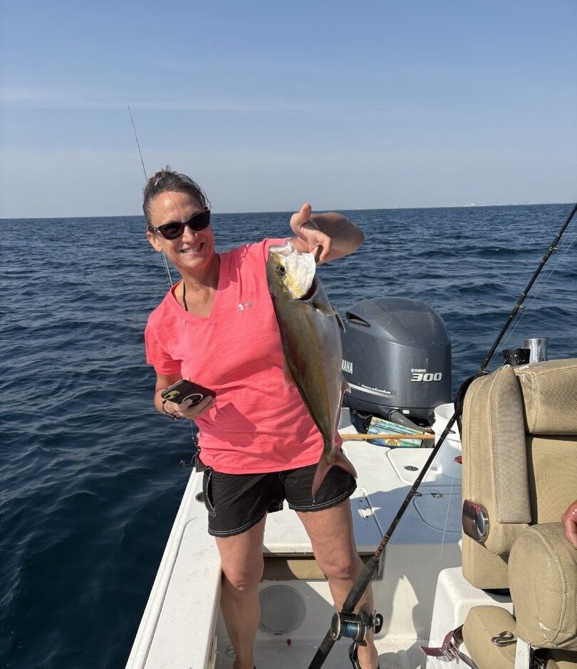 Angler holding freshly caught Greater Amberjack on fishing boat in ocean