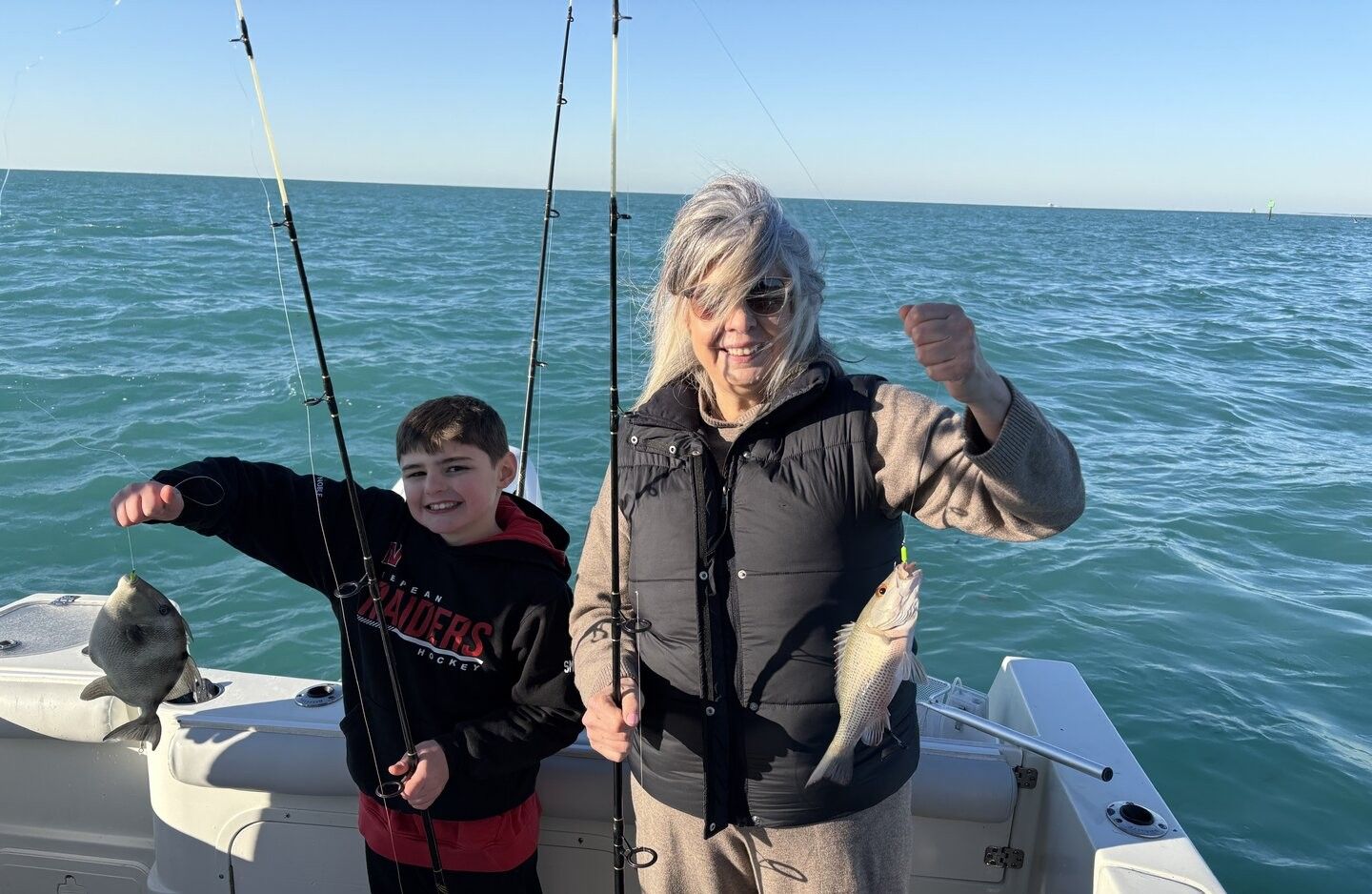 Fishing trip with caught grey snapper and grey triggerfish on boat deck with ocean background