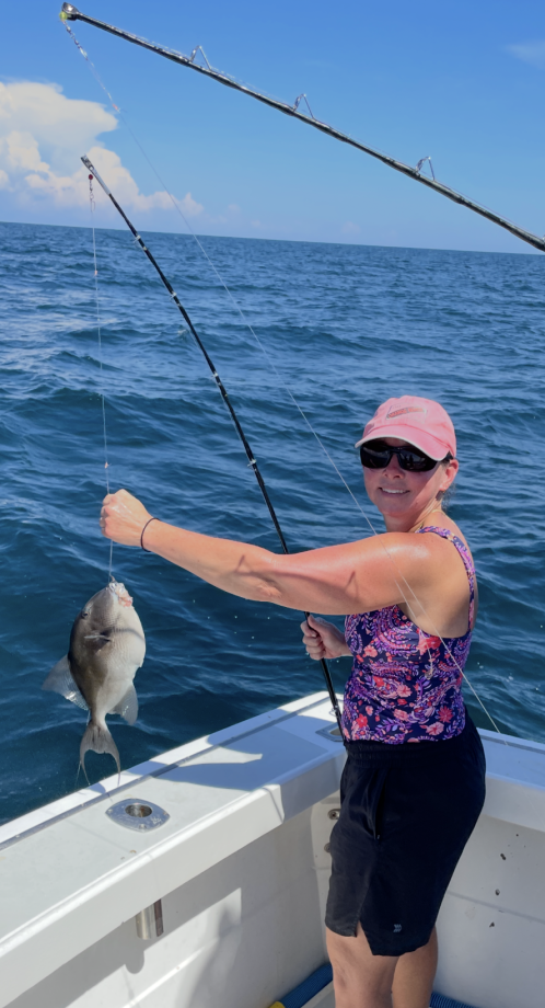 Grey triggerfish caught on fishing rod held over boat deck in ocean waters