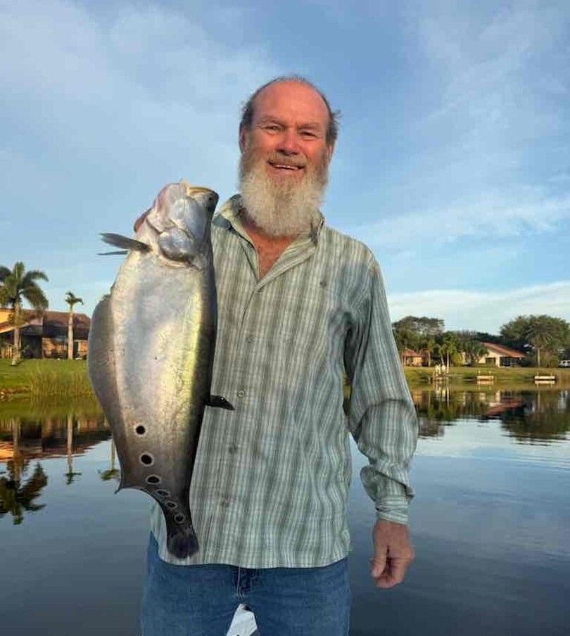 Large fish catch displayed near waterway with residential buildings in background