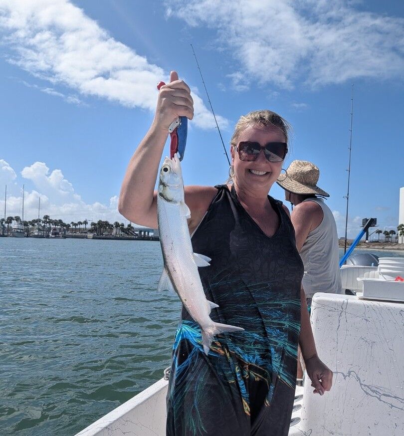 Angler holding freshly caught ladyfish on fishing boat during outdoor fishing trip