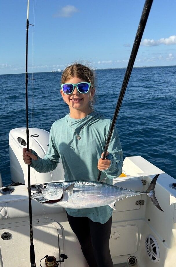 Little tunny catch displayed on fishing boat deck over blue ocean water