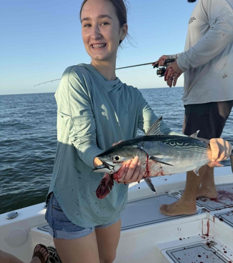Freshly caught Little Tunny held on fishing boat deck over ocean water