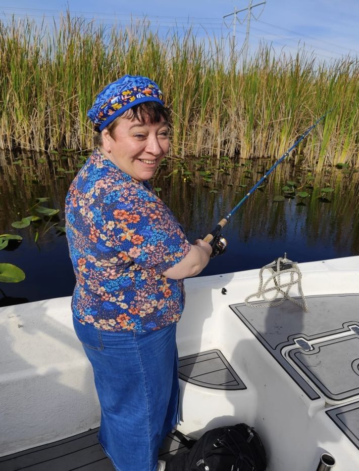 Fishing from boat in marshy waterway with tall reeds and lily pads