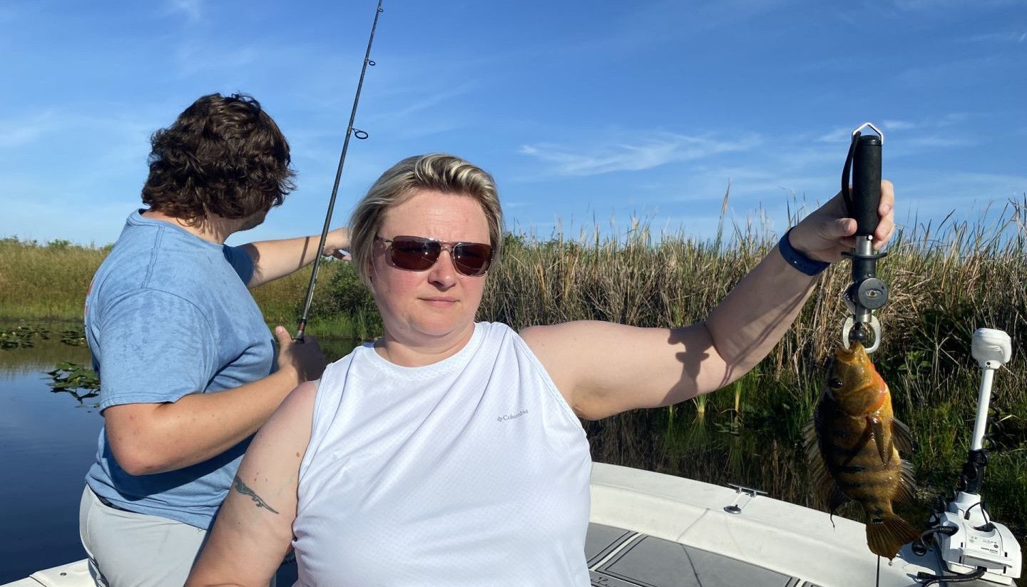 Angler holding freshly caught Mexican Mojarra on fishing boat in marsh waters