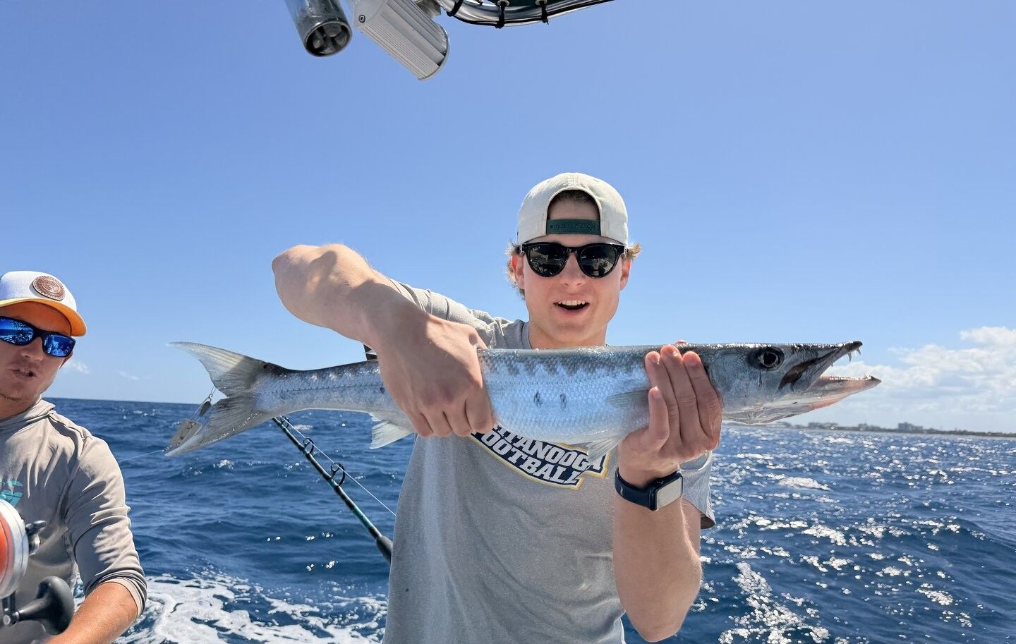 Angler holding freshly caught fish on fishing boat in ocean waters