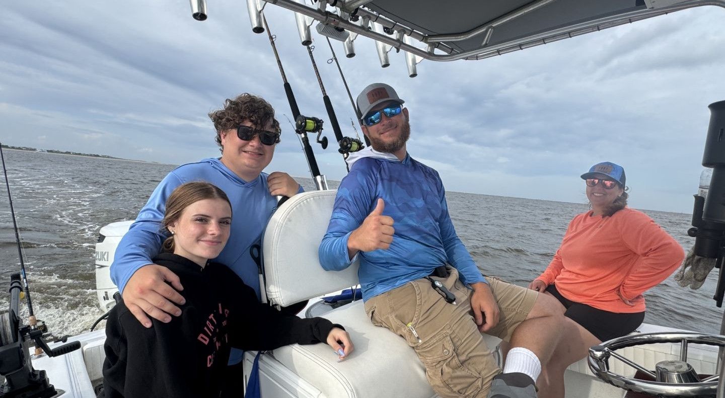 Fishing boat on open water with fishing rods mounted on outriggers under cloudy sky