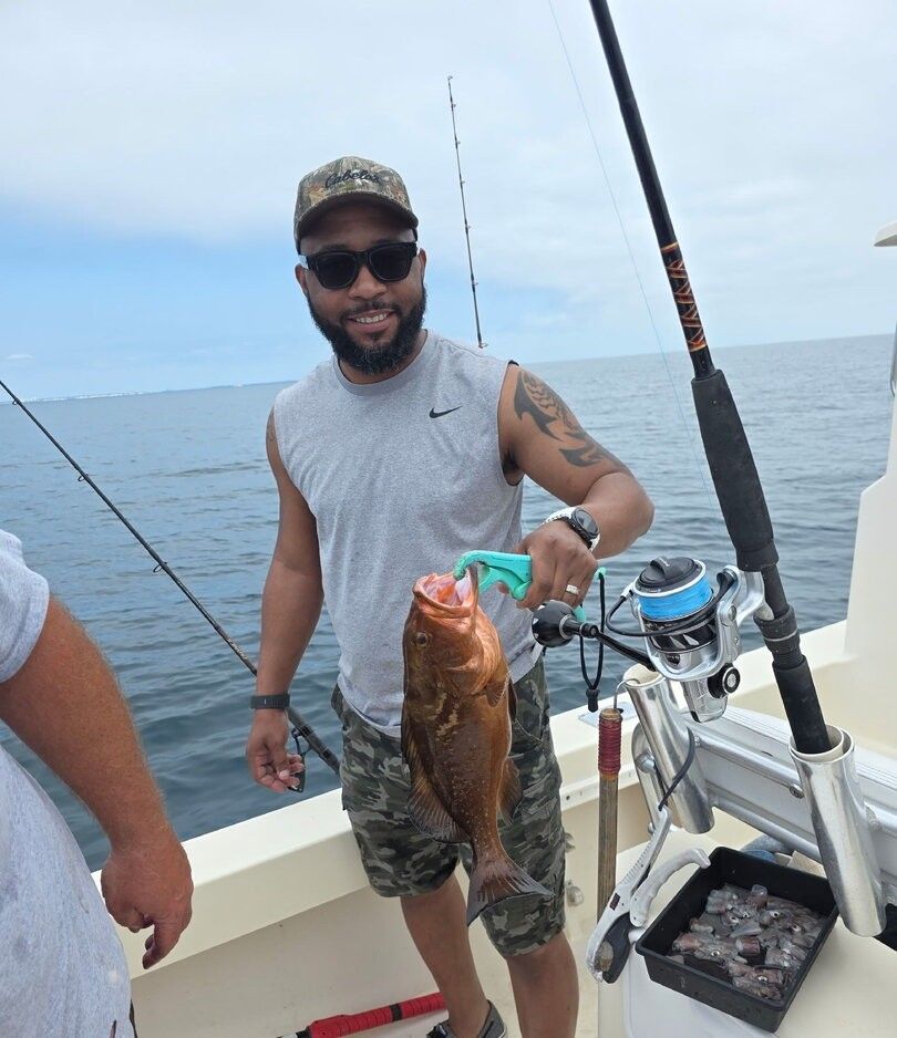 Red grouper catch displayed on fishing boat deck with fishing rods and tackle box