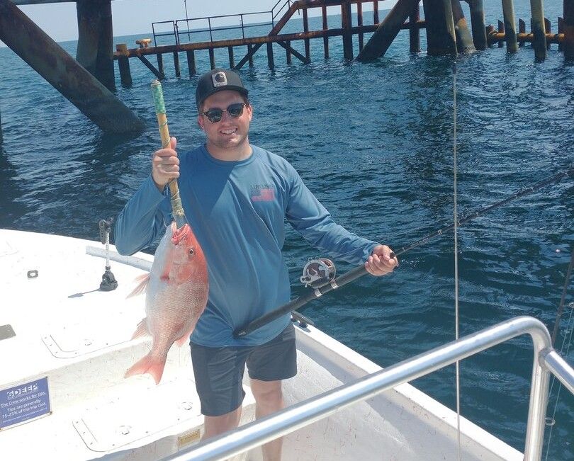 Freshly caught red snapper displayed on fishing boat deck with pier in background